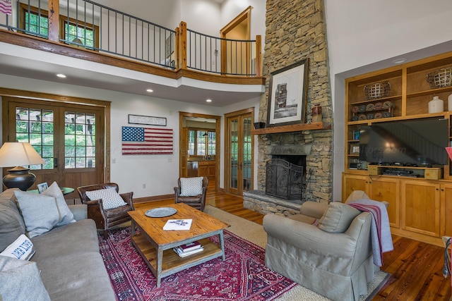 living room featuring a fireplace, a towering ceiling, and dark wood-type flooring