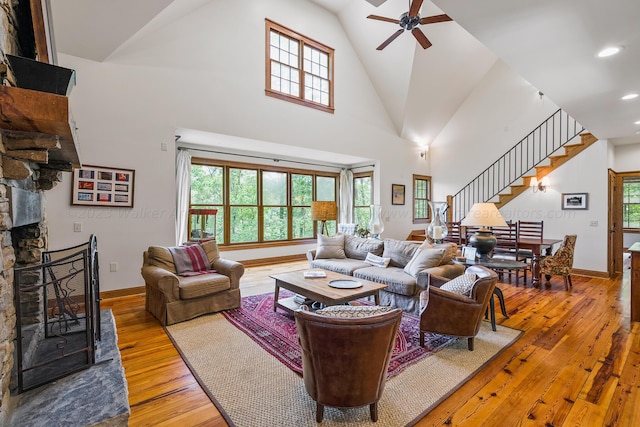 living room with a fireplace, ceiling fan, hardwood / wood-style floors, and high vaulted ceiling