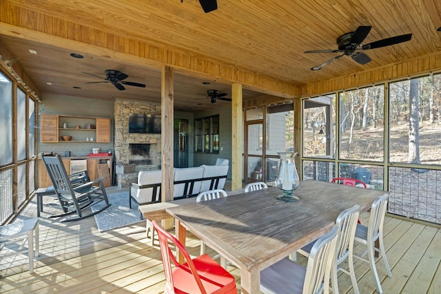 sunroom featuring an outdoor stone fireplace and wooden ceiling