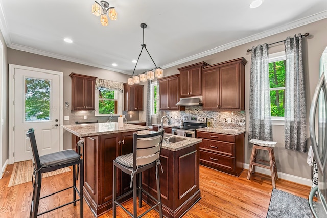 136 Grand Magnolia, Jasper, AL 35504 - kitchen with under cabinet range hood, appliances with stainless steel finishes, an island with sink, light wood-type flooring, and backsplash