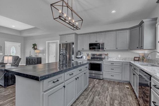 kitchen featuring wood finished floors, a sink, stainless steel appliances, gray cabinetry, and recessed lighting