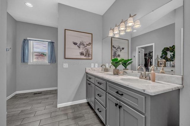 full bath with double vanity, wood finish floors, baseboards, and a sink