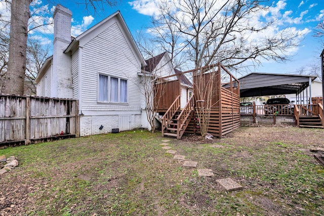 view of yard with a wooden deck, a carport, fence, and stairway