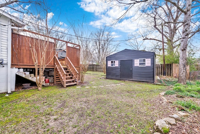 view of yard featuring an outbuilding, a storage unit, a fenced backyard, and stairs