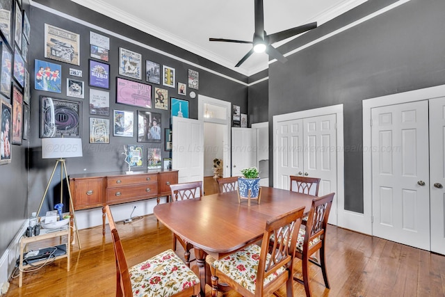 dining area with hardwood / wood-style floors, a towering ceiling, crown molding, and ceiling fan