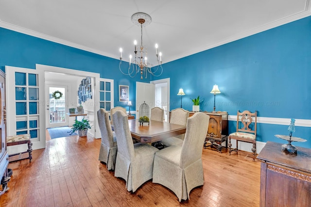 dining room featuring an inviting chandelier, ornamental molding, and wood-type flooring