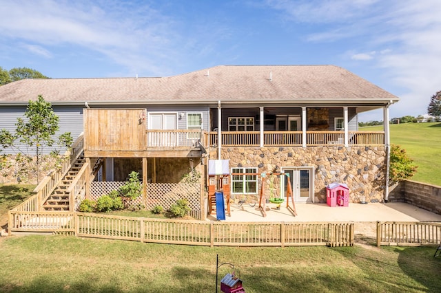 rear view of property with roof with shingles, a lawn, stairs, and a patio