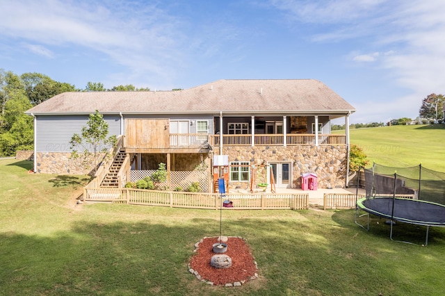 back of house featuring a yard, stone siding, stairway, and a trampoline