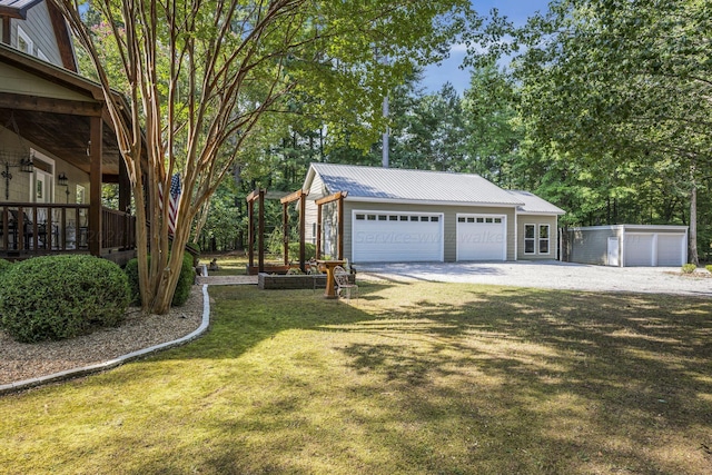 exterior space with driveway, an outbuilding, a detached garage, a lawn, and metal roof