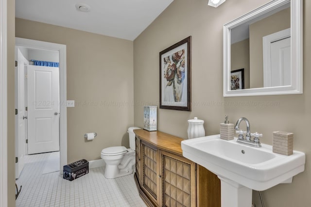 bathroom with tile patterned flooring, toilet, baseboards, and a sink