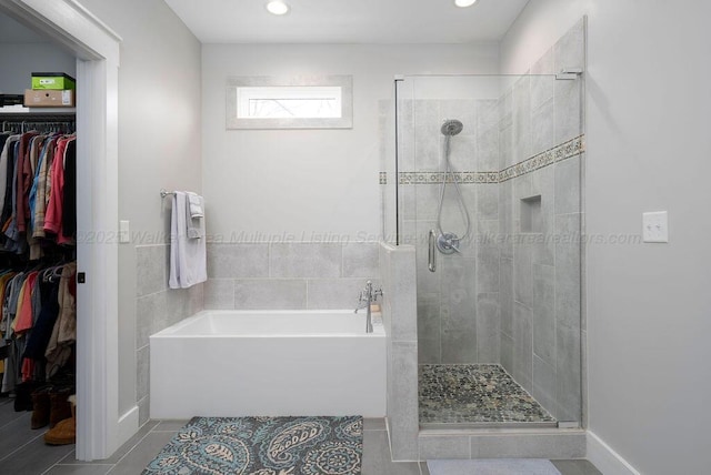 bathroom with separate shower and tub, tile patterned flooring, and tile walls