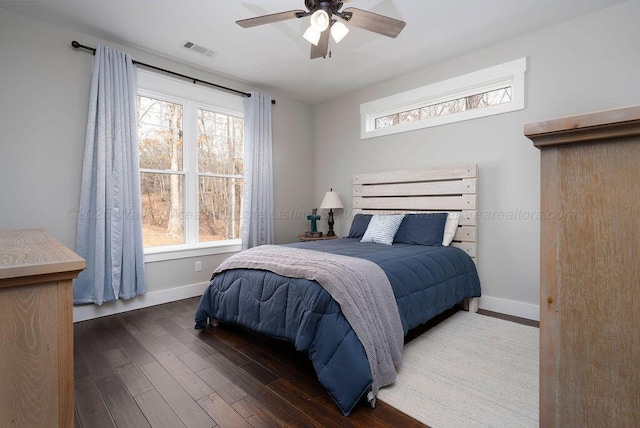 bedroom with multiple windows, dark wood-type flooring, and ceiling fan