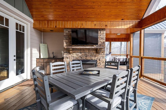 sunroom / solarium featuring lofted ceiling, wooden ceiling, french doors, and an outdoor fireplace