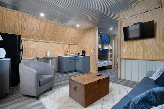 living room featuring sink, wood ceiling, wooden walls, and light hardwood / wood-style floors