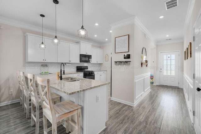 474 Meadow Way, Jasper, AL 35501 - kitchen with black appliances, white cabinets, light stone countertops, a kitchen breakfast bar, and wood finished floors
