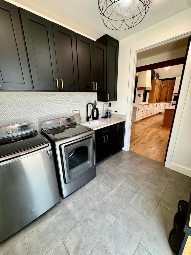 clothes washing area with washer and dryer, cabinet space, and a sink
