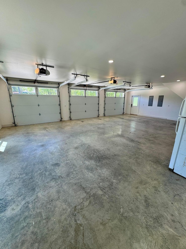 garage featuring electric panel, freestanding refrigerator, recessed lighting, and a garage door opener