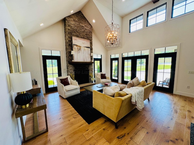 living room featuring high vaulted ceiling, an inviting chandelier, light wood finished floors, a fireplace, and recessed lighting