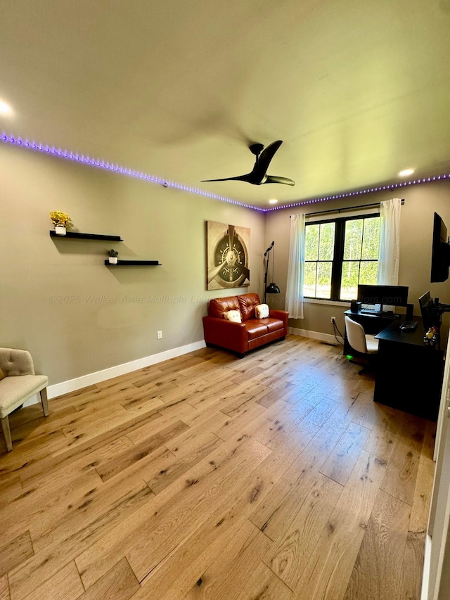 living area featuring hardwood / wood-style flooring, baseboards, and a ceiling fan
