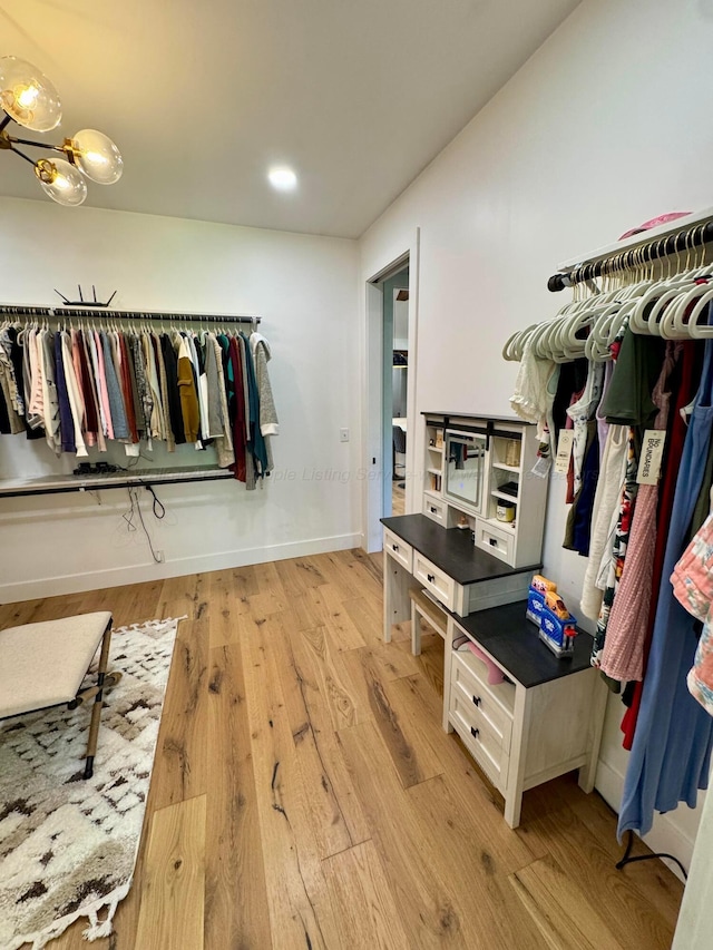 spacious closet featuring a notable chandelier and light wood-style floors