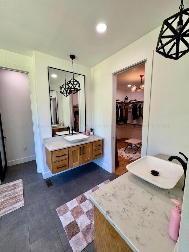 bathroom with recessed lighting, visible vents, vanity, a walk in closet, and baseboards