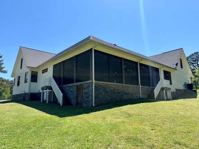 rear view of property featuring stairway, a lawn, and a sunroom