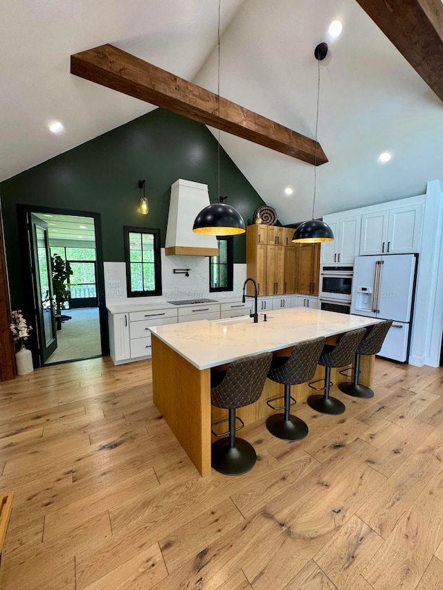 kitchen with light wood finished floors, black electric cooktop, a sink, and white fridge with ice dispenser