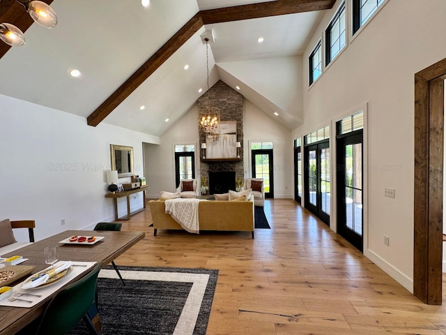 living room with high vaulted ceiling, a wealth of natural light, beam ceiling, and light wood finished floors