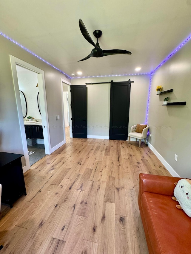 unfurnished bedroom with light wood finished floors, baseboards, recessed lighting, and a barn door