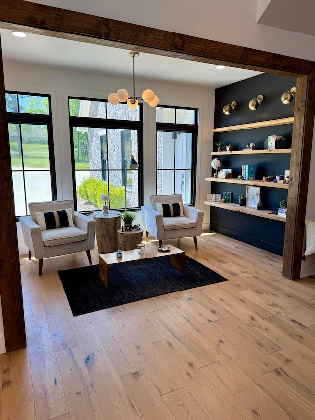 living area featuring light wood-type flooring, an inviting chandelier, and beam ceiling