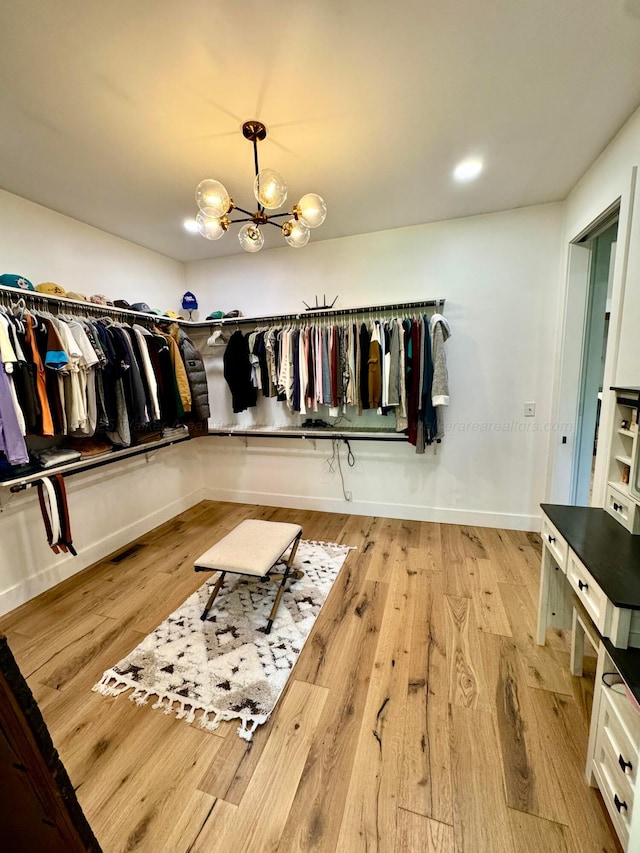 spacious closet with a notable chandelier and light wood finished floors