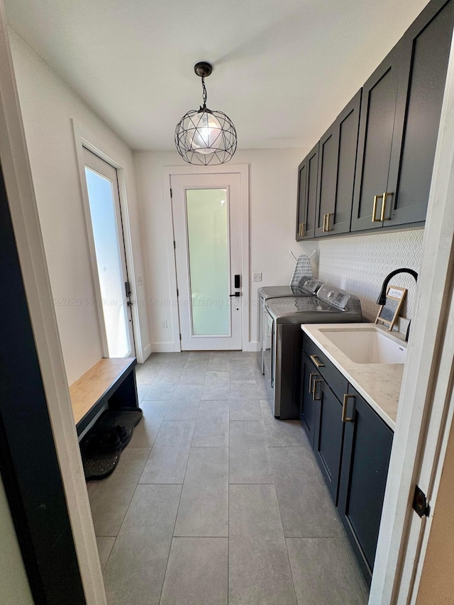 washroom with washing machine and clothes dryer, a sink, light tile patterned flooring, baseboards, and cabinet space