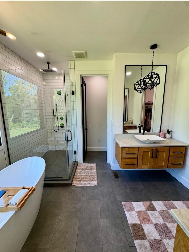 bathroom with visible vents, vanity, baseboards, a freestanding tub, and a stall shower