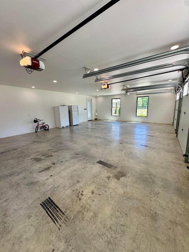 garage featuring freestanding refrigerator, recessed lighting, and a garage door opener