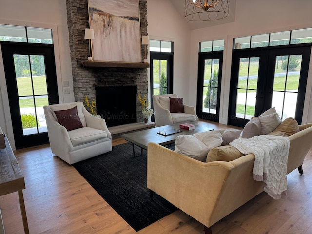 living room with high vaulted ceiling, a fireplace, an inviting chandelier, and light wood-style flooring