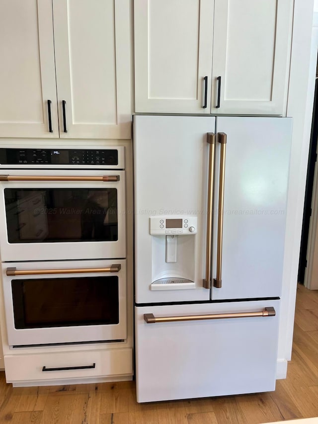 details with white cabinets, light wood finished floors, and white appliances