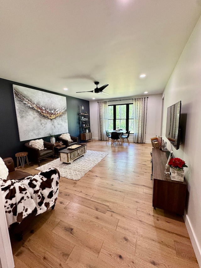 living area featuring baseboards, a ceiling fan, light wood finished floors, and recessed lighting