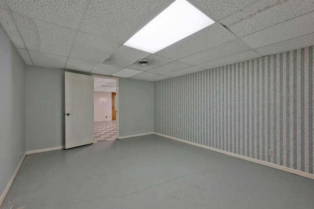 basement featuring wallpapered walls, visible vents, a drop ceiling, and baseboards
