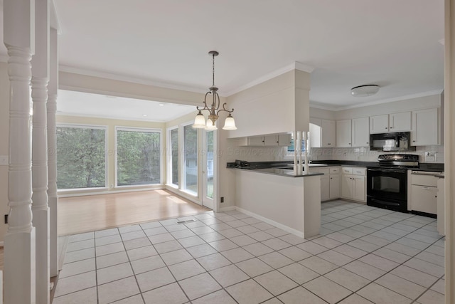 kitchen featuring light tile patterned floors, dark countertops, black appliances, and a healthy amount of sunlight