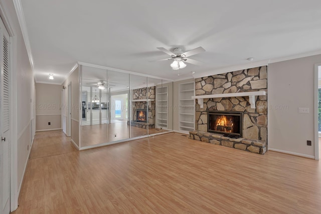 unfurnished living room featuring baseboards, wood finished floors, ceiling fan, a fireplace, and ornamental molding