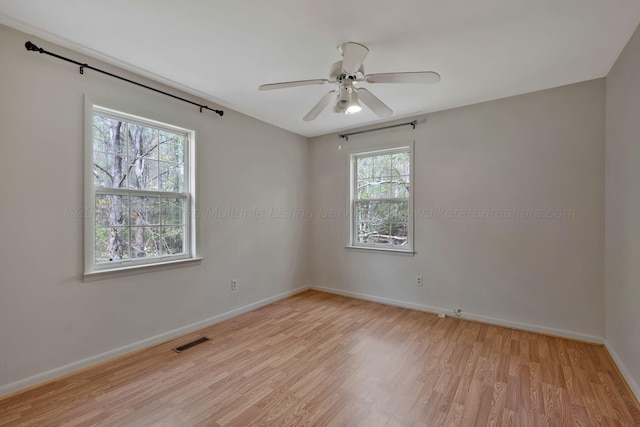 empty room featuring baseboards, a ceiling fan, visible vents, and light wood-style floors