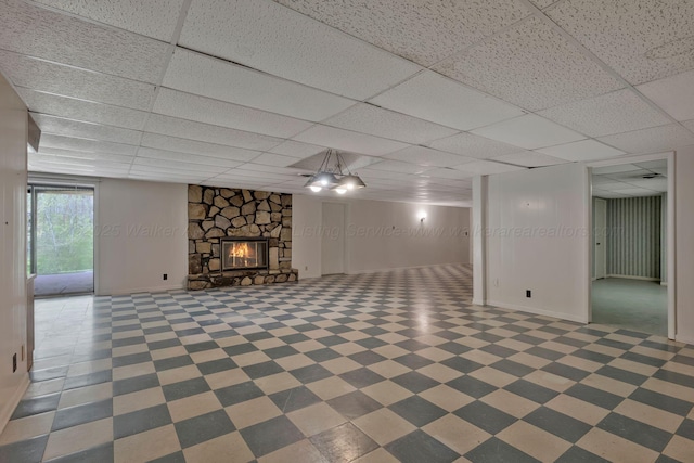 basement featuring a stone fireplace and a drop ceiling