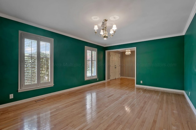 empty room with plenty of natural light, visible vents, a chandelier, and crown molding