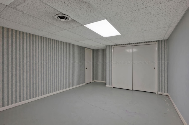 unfurnished bedroom with baseboards, finished concrete floors, visible vents, and a paneled ceiling