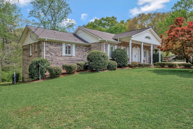 neoclassical / greek revival house featuring brick siding, a shingled roof, and a front yard