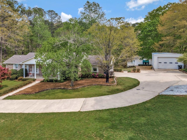view of front of home featuring a porch, a front lawn, curved driveway, and an outbuilding
