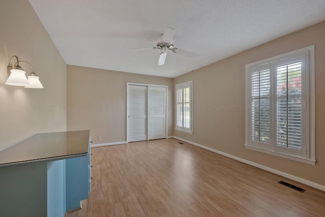 interior space featuring baseboards, multiple windows, visible vents, and light wood-style floors