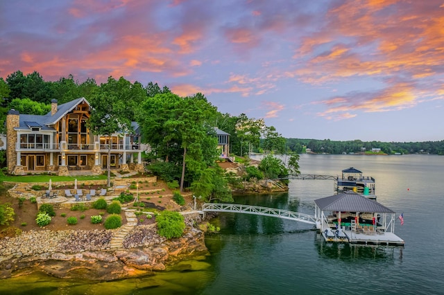 dock area with a balcony, a water view, and a patio area