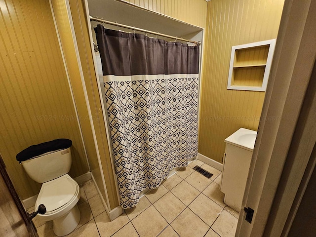 bathroom with wood walls, tile patterned floors, and toilet