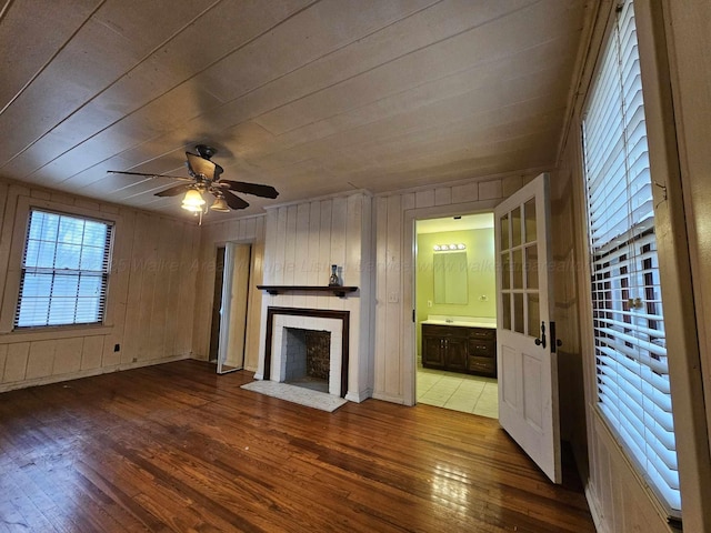 unfurnished living room featuring ceiling fan, hardwood / wood-style floors, and wooden walls